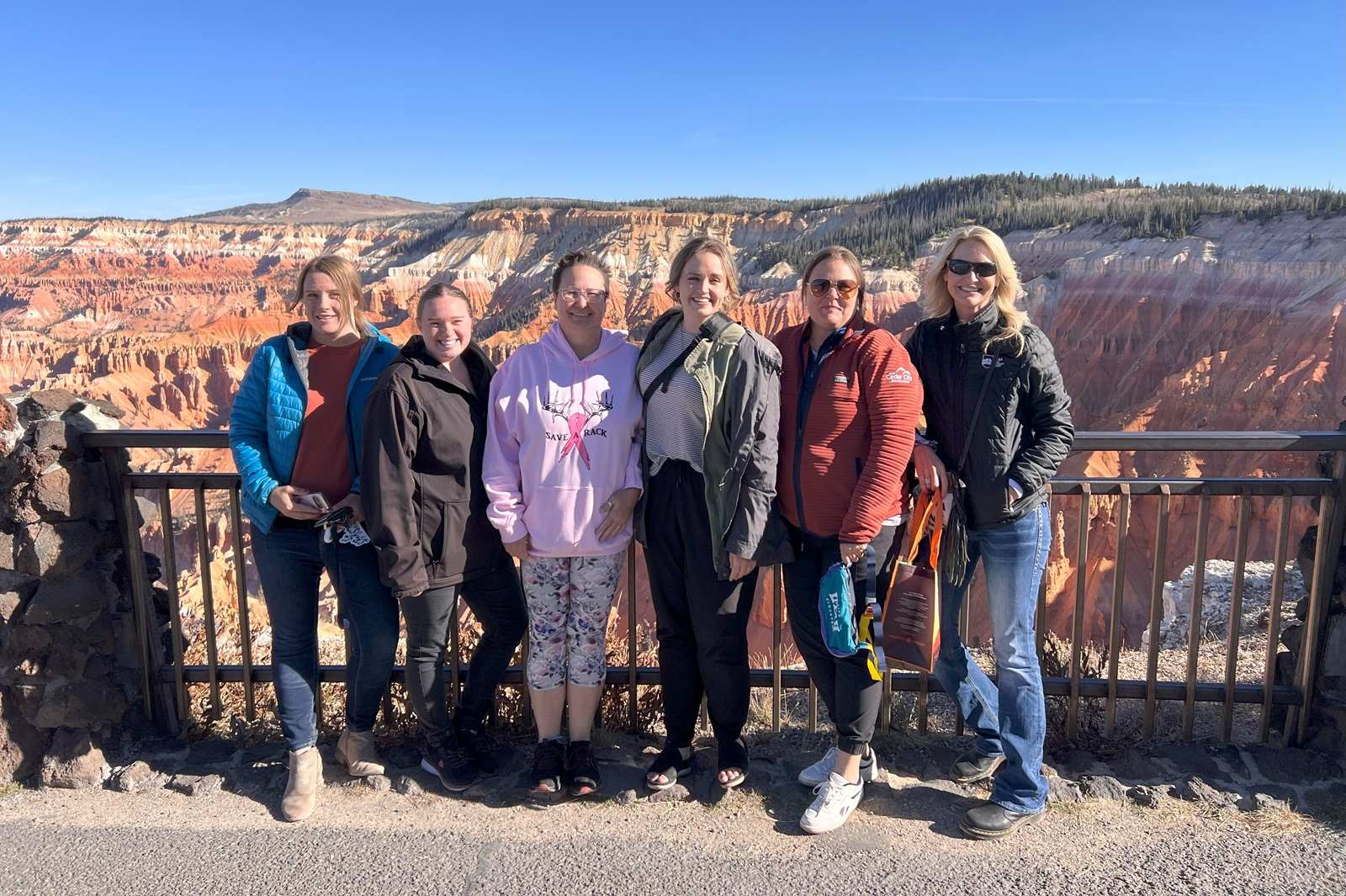 Overlooking Cedar Breaks National Monument with red rock cliffs in the background and group of people in front.