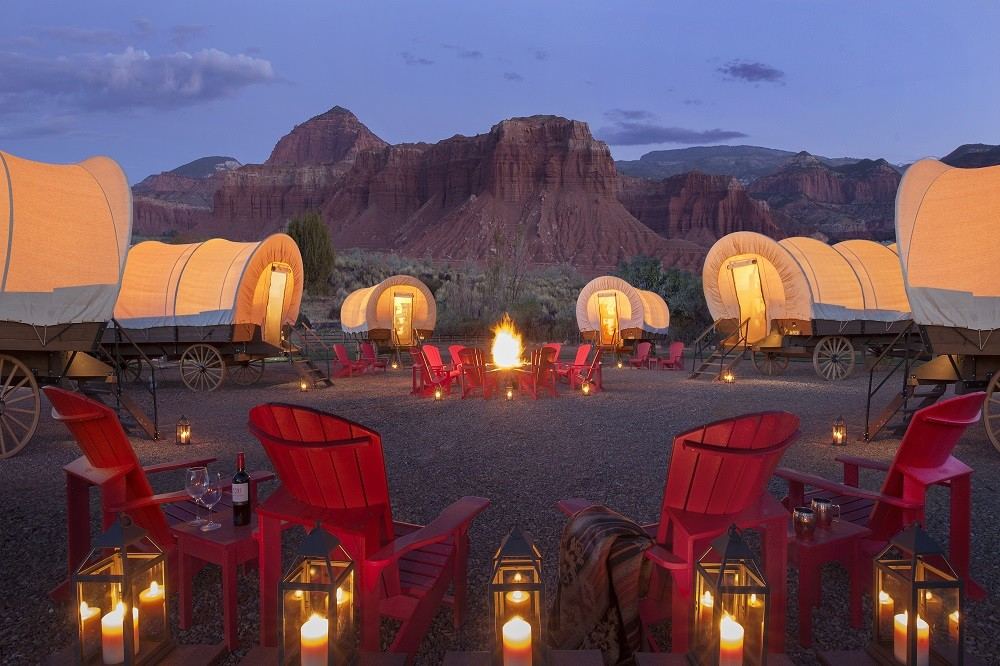 Evening covered wagons in a circle with lounge chairs and lanterns