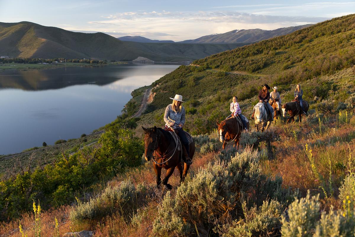 Group riding horses on a mountain with a river