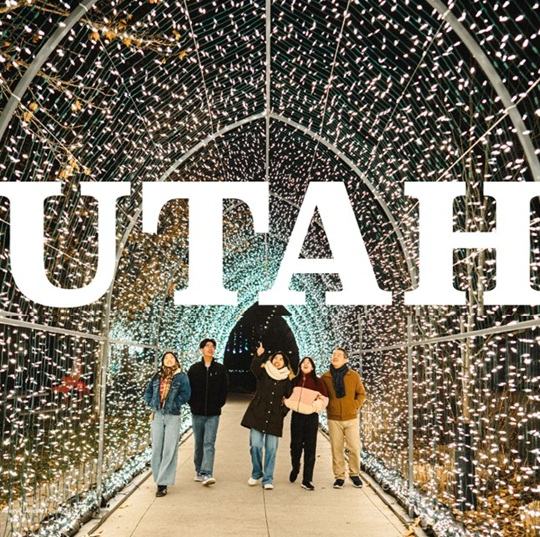 Group of people walking under tunnel with many small lights and the word Utah overlay