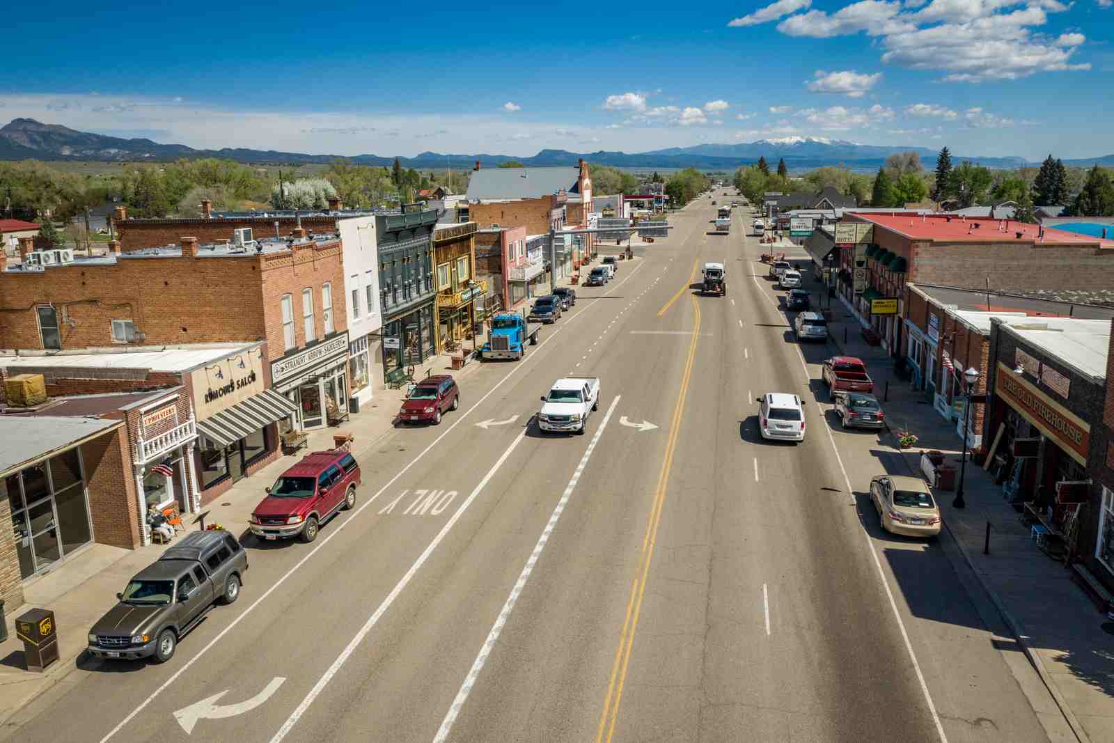 Above view of main street with businesses and cars and in the background are trees and mountains