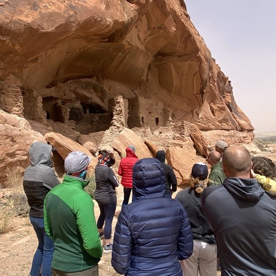 Group of people looking at ancient Native American cliff house ruins