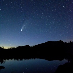 Night sky with comet over mountains and lake